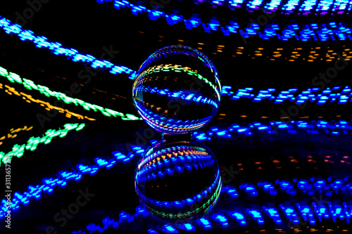 brilliant view of long exposure light painting experiment with lens ball placed over glass for reflection using a tripod inside a complete dark room for Christmas festival celebration