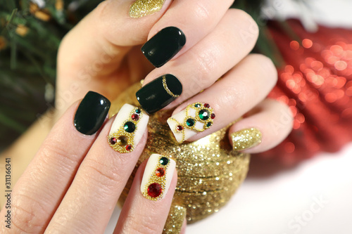 New year's fashionable beautiful festive manicure on short square nails with green lacquer color, with Golden sequins, bouillon and rhinestones of different colors .Christmas nail art.