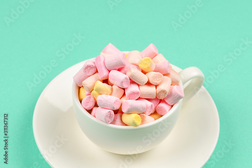 Cup with marshmallow on a green background. Copy space.