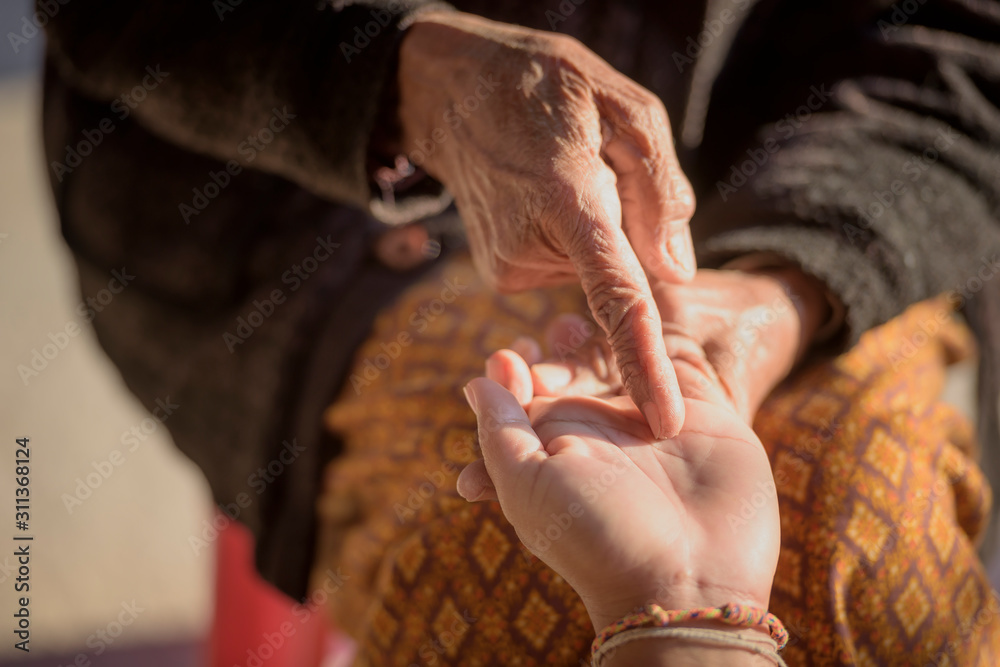 The fortune teller reads a fortune line on the palm or the hand of a mysterious woman. Concept of palmistry.