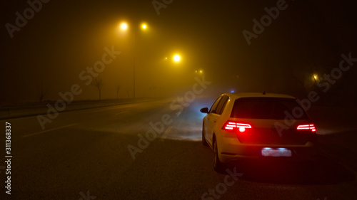 road lighting poles and car headlight on a foggy night © Vahit Telli