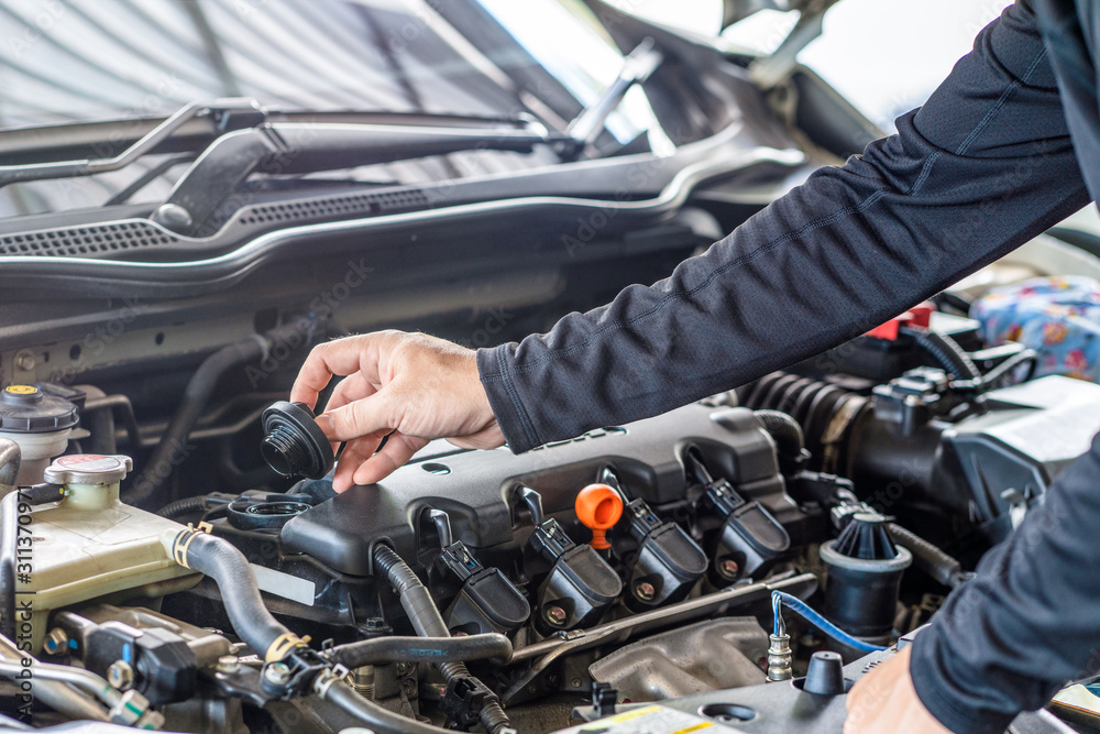 Hand of mechanic man open cap engine oil fill, inspection and maintenance car service Hand of mechanic man open cap engine oil fill, inspection and maintenance car service