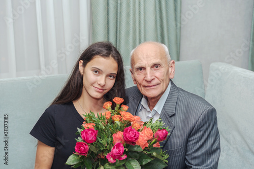 grandfather and granddaughter sitting at home with bouquet of flowers