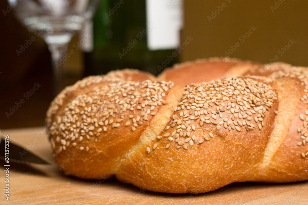 Round loaf of Italian bread with sesame seeds on cutting board