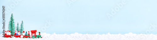 Fotografia Christmas train over blue background with New Year spruce trees on snow