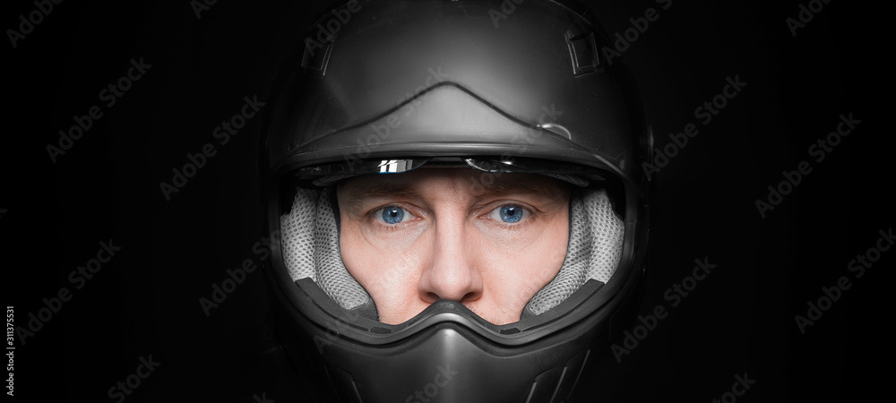 Man in motorcyclist helmet on dark studio background. Closeup. Man in motorcyclist helmet on dark studio background. Closeup.