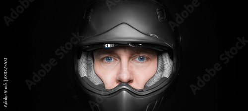 Man in motorcyclist helmet on dark studio background. Closeup. photo