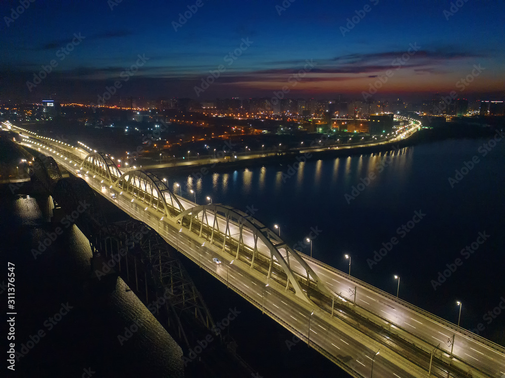 Fototapeta premium Busy traffic on the lantern-lit bridge of the night city.