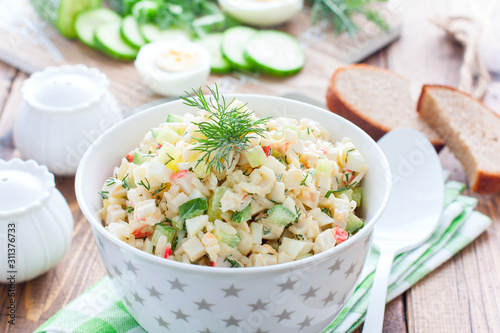 Salad with crab sticks, fresh cucumbers and rice in a white bowl, horizontal