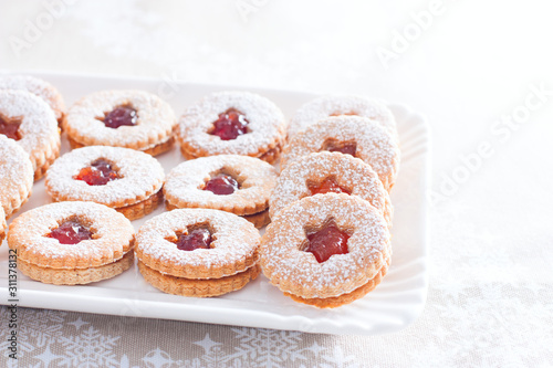 Traditional Christmas linzer cookies on a white dish, horizontal