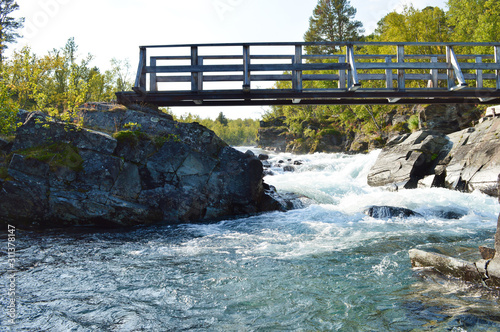 Bridge over wild river and rapids near Kungsleden trail in Abisko national Park, Sweden photo