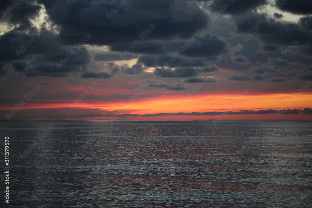 Fototapeta premium Sunset in the sea with dark clouds.