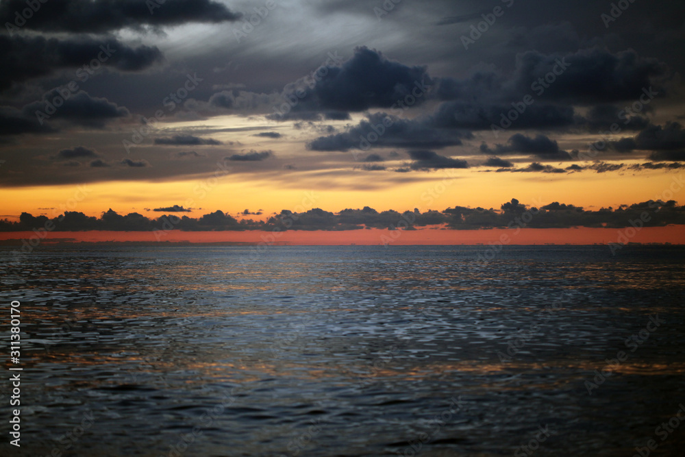 Sunset in the sea with dark clouds.