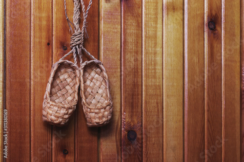 Old Russian shoes - souvenir bast shoes hanging on a light wood wall. photo