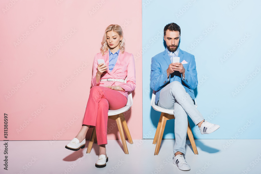 Naklejka premium attractive woman and handsome man using smartphones on pink and blue background