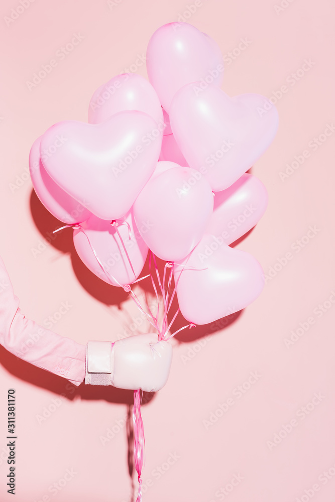 Φωτογραφία Cropped view of woman in boxing glove holding balloons on pink background