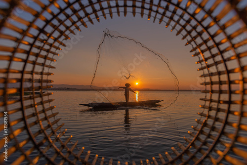 Picture of Asian fishermen on a wooden boat Thai fishermen catch fresh water fish in the natural river, traditional Thai fishermen at the morning sun on the lake of Thailand