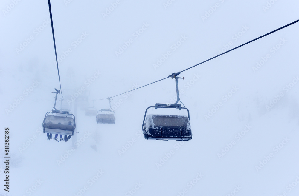 Frozen ski lifts covered with snow in misty weather and foggy day. Hard winter conditions, snowfall and fog. Dolomites, Italy, Europe. Frozen ski lifts covered with snow in misty weather and foggy day. Hard winter conditions, snowfall and fog. Dolomites, Italy, Europe.