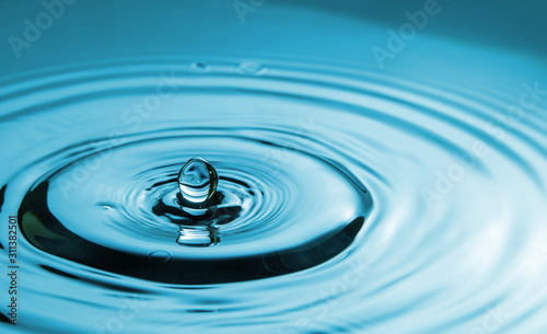 Closeup Water drop falling on the surface of the water and beautiful circular wave ripple, fresh natural mineral water drink water concept