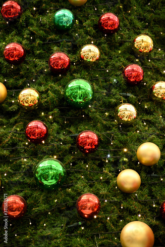 Christmas background, card, multi-colored balls with garlands hang on coniferous branches. On a fir-tree yellow, red and other balls are placed.