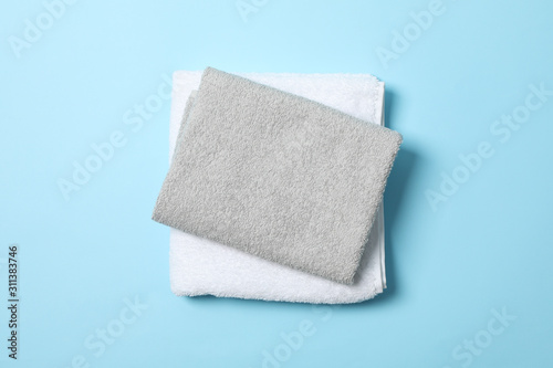 Folded towels on blue background, top view and space for text