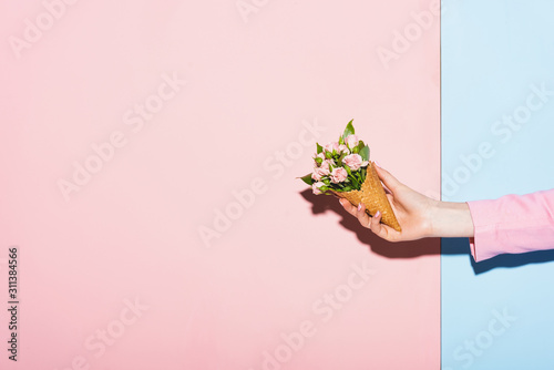 cropped view of woman holding bouquet on pink and blue background