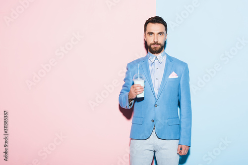 serious man holding cocktail on pink and blue background © LIGHTFIELD STUDIOS