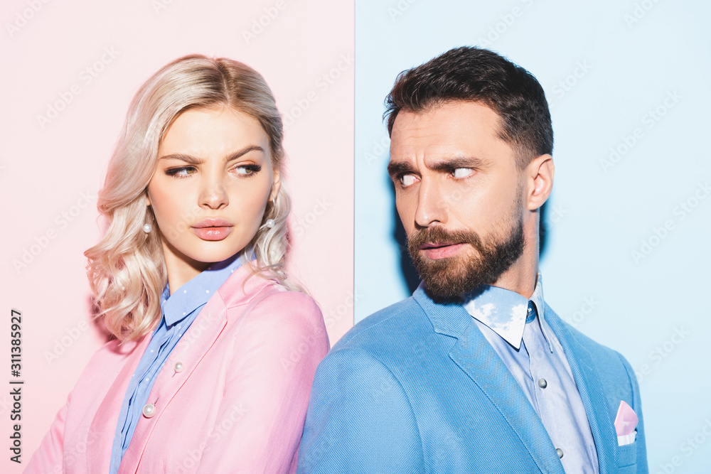 irritated woman and handsome man looking at each other on pink and blue background irritated woman and handsome man looking at each other on pink and blue background
