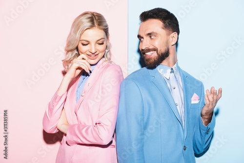 attractive woman and handsome man smiling on pink and blue background