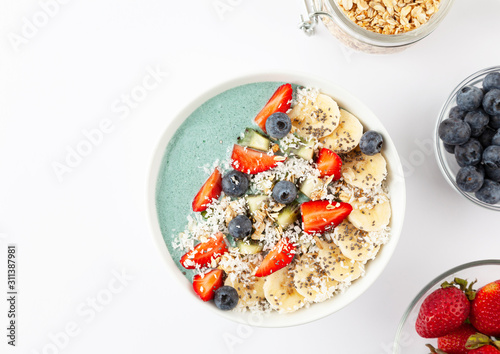Detox breakfast smoothie bowl with spirulina, blueberry, strawberry, granola, kiwi, banana, coconut and chia seeds. Spirulina smoothie with berries and fruits in bowl. 