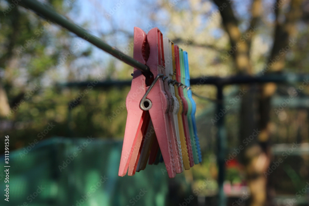 Colorful clothespins hanging in a row on clothesline in the garden