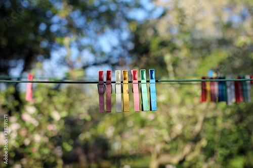 Colorful clothespins hanging in a row on clothesline in summer