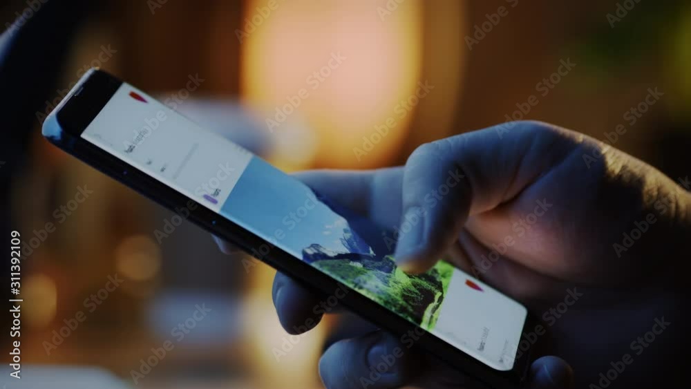 Close-up Macro: Person Holding and Using Smartphone, Browsing through Pictures on Social Network Wall. Finger Scrolling Social Media App Feed: Travel, Animals, Food. Mock-up Application Design