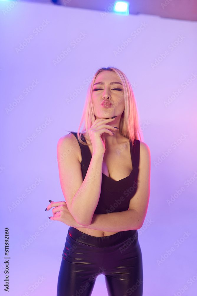 Beautiful woman in black leather pants on a pink background Beautiful woman in black leather pants on a pink background