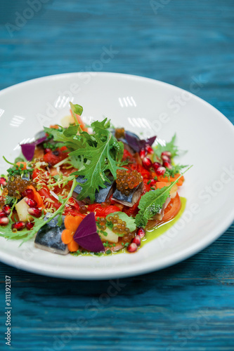 Escabeche fish dish with caviar: mackerel in marinade with vegetable, on a plate on the wooden blue background. photo