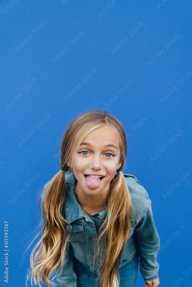 Blond girl looking at camera and sticking out her tongue Stock Photo