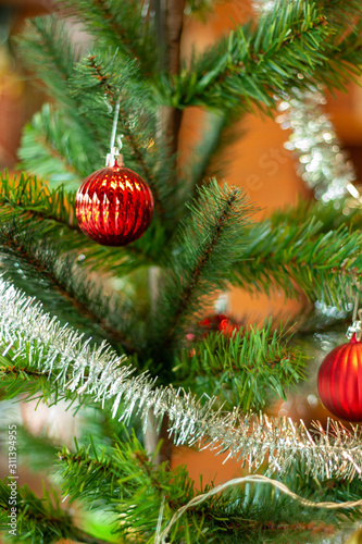 Red ball on a Christmas tree with a garland on the background of a wooden wall.