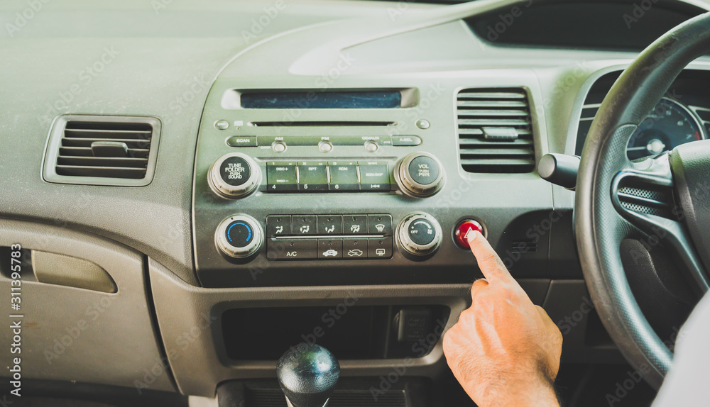 Fototapeta premium Finger male pressing a push button emergency lights in his car. Safety first insurance concept