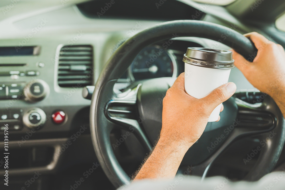 Hands male driving car paper cup coffee.