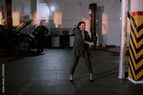 Good looking manager woman in a suit attractive look dancing in a garage after they finished the work day