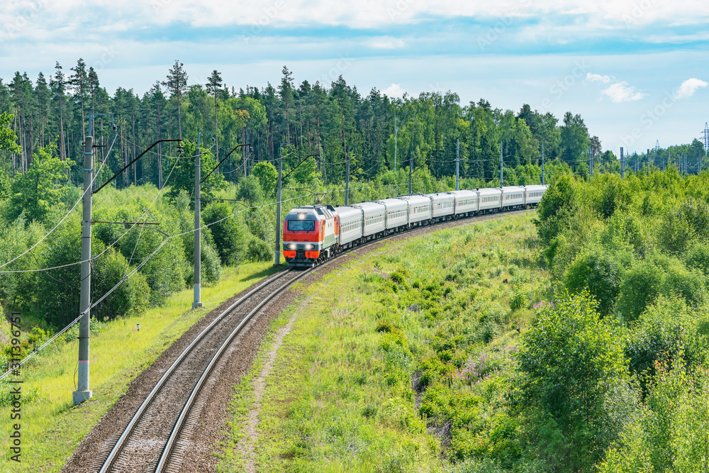 Obraz premium Passenger train approaches to the station at summer morning time.