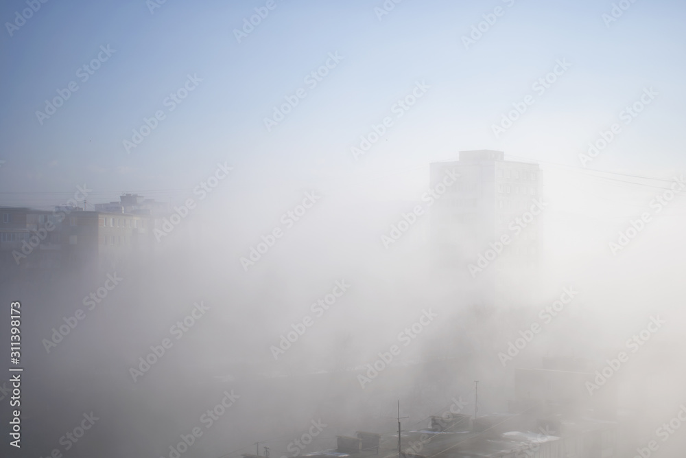 White clouds of fog envelop buildings at residential district. Urban panorama