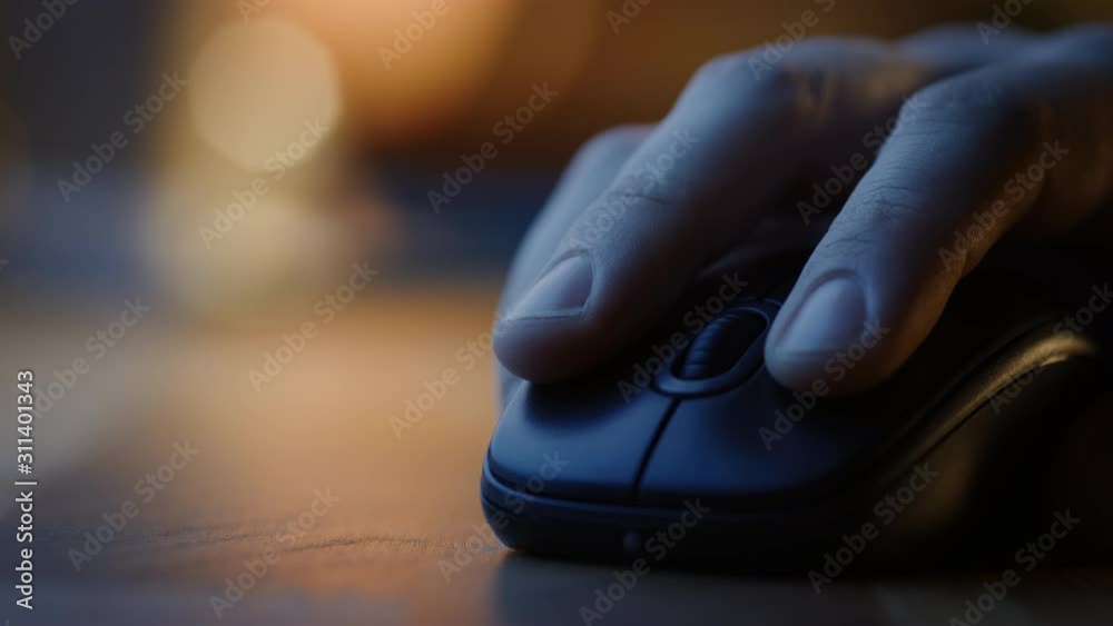 Close-up Macro Shot: Person's Hand Using Wireless Computer Mouse, Scrolls through Apps and Websites with a Wheel and Clicks on Buttons. In the Background Evening Light Close-up Macro Shot: Person's Hand Using Wireless Computer Mouse, Scrolls through Apps and Websites with a Wheel and Clicks on Buttons. In the Background Evening Light