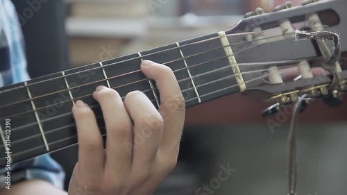 Young boy learn to play guitar, view close up to his hand. Guitarist edit guitar strings.