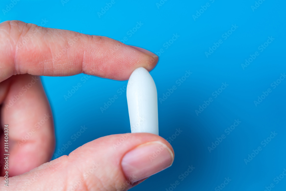 White suppository for anal or vaginal use in patient's hand on blue background. Medical candles for the treatment of Candida, thrush, hemorrhoids, inflammation and fever. Effective drug. Copy space White suppository for anal or vaginal use in patient's hand on blue background. Medical candles for the treatment of Candida, thrush, hemorrhoids, inflammation and fever. Effective drug. Copy space