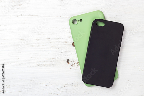 Green and black phone cases on wooden table background