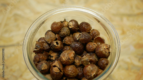 Soap nuts Indian soapberry or washnut glass jar cup, Sapindus mukorossi reetha or ritha from the soap tree shells are used to wash clothes to put drum washing machines. Nuts saponin plant fruit seeds photo