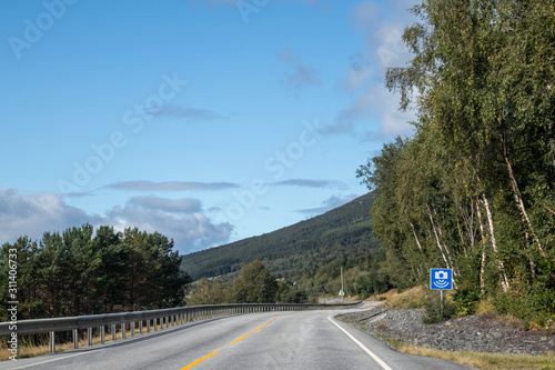 Norway road with radar speed limit sigh near road. Traveling by car, driving nature tourism. Dramatic skyscape northern scandinavian sky