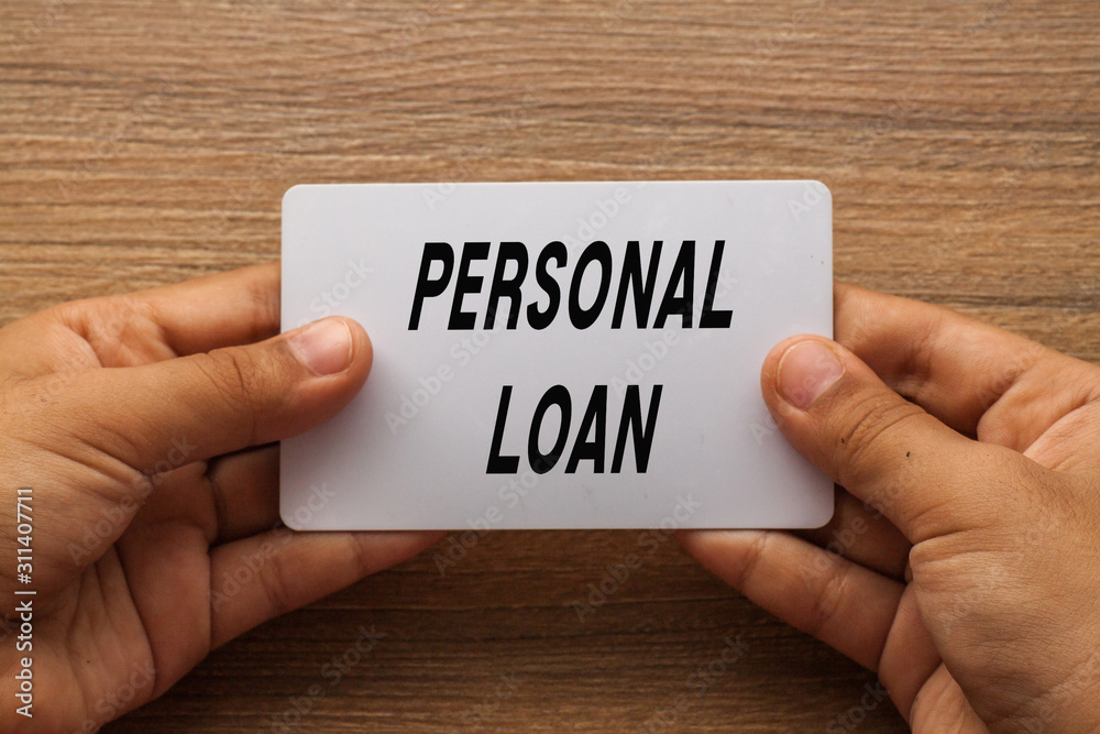 Personal Loan written on white card holding with two hands Personal Loan written on white card holding with two hands