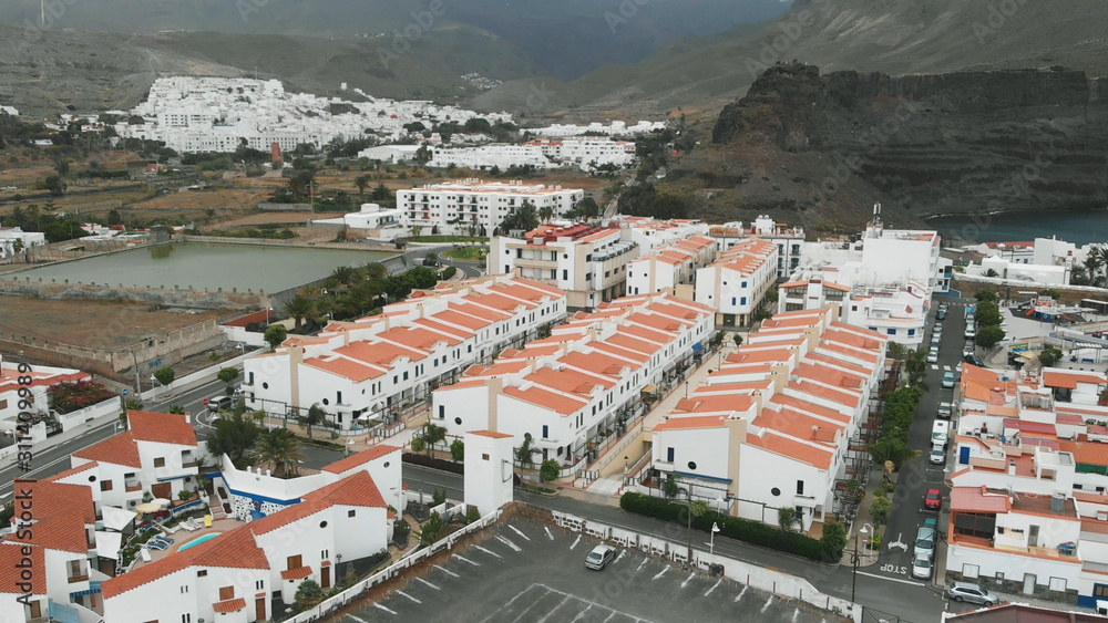 Above. The village at the foot of the misty mountains - white houses with an orange roof, Spanish architecture, holiday homes. Bird's eye view.